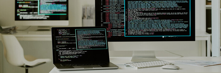 Wall Mural - Website banner of monitors of laptop and computer with codes, devices located on work desk in office