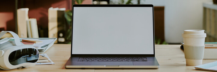 Wall Mural - Website banner with black laptop with blank screen surrounded by VR goggles and cup of coffee