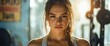 © Martinah - Intense gaze of a determined woman in the sunlit gym, showing the power of sport