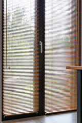 Fototapete - Full view of floor-to-ceiling glass doors covered with horizontal wooden blinds. The blinds on windows are operated with a wooden stick and a rope. Blinds are fixed at the bottom with a cable. 