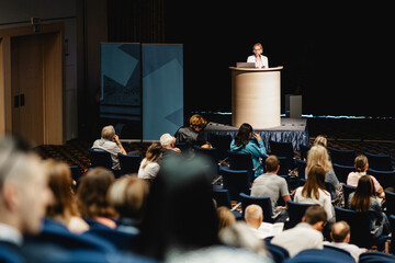 Wall Mural - female speaker giving a talk on corporate business conference. unrecognizable people in audience at 