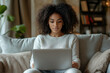 © Midea  - Woman sitting on couch, focused on laptop screen, surrounded by cozy home decor.