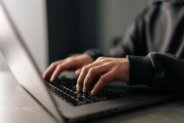 close-up hands of unrecognizable programmer male typing on laptop keyboard, immersed in software dev