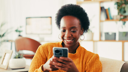 Fototapete - Black woman, phone and happy on sofa in home, texting and relax with web chat in living room. African person, smartphone and click on mobile app with notification, contact and social media in house