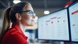 © NovaVision - Focused businesswoman reviews data on multiple computer monitors in a modern office setting.