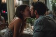 © Marcos Kulenkampff - A couple shares a romantic kiss across the dinner table at a restaurant. The scene is intimate and warm, illuminated by soft light.