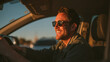 © Jhati - Man driving car wearing sunglasses at sunset happy road trip travel and lifestyle automotive adventure