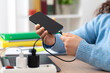 © cunaplus - Close up of a business woman hand plugging charger cable to a smart phone at home
