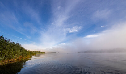 Wall Mural - a foggy morning with a blue sky and a lake