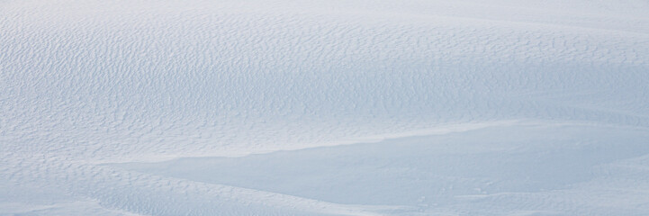 Wall Mural - beautiful winter background with snowy ground. natural snow texture. wind sculpted patterns on snow 