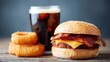 © kiimoshi - Delicious cheeseburger with bacon accompanied by a refreshing cola and crispy onion rings, perfect for a satisfying meal or casual dining experience.