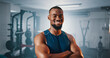 © peopleimages.com - Portrait, fitness and confident black man in gym for exercise, muscle or strength training for health. Smile, wellness and person at workout club as bodybuilder for sports, trainer and arms crossed
