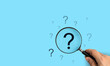 © Chan_Studio - Focusing on a large question mark, A hand holding a magnifying glass over a large question mark