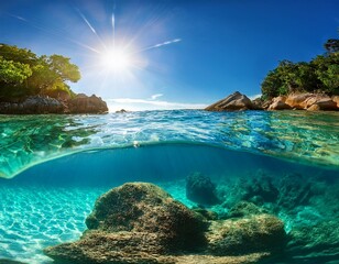 a split view of crystal clear water and a sunny sky with a bright sun showcasing underwater rocks ri