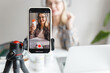 © shurkin_son - Selective focus on phone on tripod recording video of senior qualified nutritionist female blogger of 60s holding bottle of food supplement, giving advice and tips on how boost health, immune system