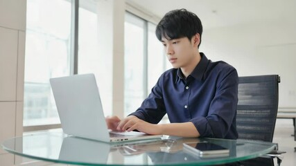 Wall Mural - a person sitting at a table with a laptop, likely doing work or checking email.