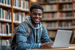 © Color Forge - Dedicated smiling black male student engaged in online learning at college library, using laptop to study, surrounded by bookshelves, Generative AI