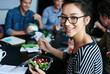 © ArcursPI/peopleimages.com - Meeting, food and portrait of woman with salad in office for team building lunch for collaboration. Discussion, smile and business female designer with colleagues eating healthy meal in workplace.