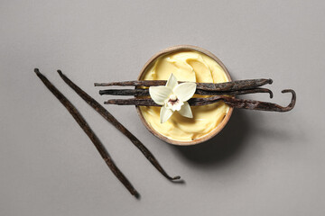 Wall Mural - bowl of tasty pudding, vanilla sticks and flower on color background