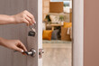 © Pixel-Shot - Female hands with key from her new flat opening door in room, closeup