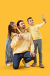© Pixel-Shot - Happy father with his little children taking selfie on yellow background