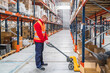 © Koldo_Studio - Warehouse worker maneuvering a pallet jack loaded with boxes in a large distribution center, managing logistics and goods efficiently