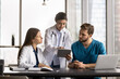 © fizkes - Mentorship in healthcare. Smiling young woman doctor mentor supervisor teach diverse couple interns explain mentees diagnosis using patient health data electronic xray image on digital tablet screen