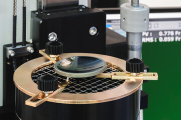Poster - An optical lens on a bench in a laboratory is tested for quality