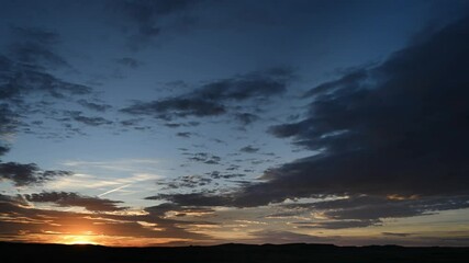 Wall Mural - time lapse of sunset with colorful sky and multi-colored clouds with distant rolling hills