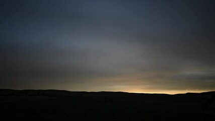 Wall Mural - time lapse of orange, pink and blue evening clouds above distant prairie hills