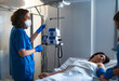 © Carmen - Nurse preparing infusion pump for patient lying in hospital bed