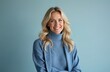 © Maryna - Smiling blonde woman portrait. Happy, beautiful female in blue sweater poses at studio on blue background. 35 year old caucasian woman with natural look smiles, wearing blue, happy person, lifestyle.