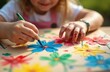 © Maryna - Close-up view child hands drawing flower with blue marker. Kid creates colorful art at summer camp or kindergarten. Learning about nature through creativity, eco-friendly craft concept.