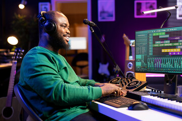 Leinwandbilder - Confident music producer operating on mixing console in home studio, producing new tunes for a song and editing volume levels in daw platform. Sound engineer recording audio files.
