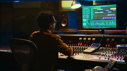 Leinwandbilder - African american sound designer operates control desk mixer and audio software for editing tracks. Producer works with switchers, buttons, sliders, motorized Faders to play hit song. Camera A.
