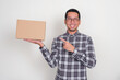 © KrishnaTedjo - A man smiling happily while pointing at blank cardboard box that he holds