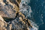 Blue sea rolls onto the rocky shore. Top view