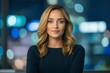 © Regina Gafarova - Beautiful professional female news anchor sits at desk, confidently looking at camera against slightly blurred background of modern newsroom. Concept of media expertise, confidence, live broadcasting.
