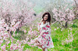 © dmitriisimakov - woman smiling in flower dress in spring blooming garden