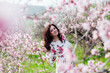 © dmitriisimakov - woman walking in flower dress in spring blooming garden