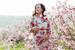 © dmitriisimakov - woman walking in flower dress in spring blooming garden