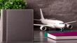 © SatoruArt - Travel preparation with passport, airplane model, and books on a gray background