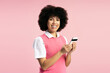 © Maria Vitkovska - Smiling young woman using smartphone on pink background