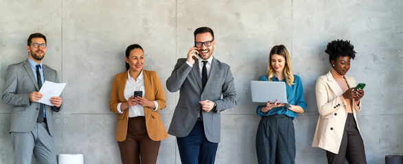 busy smiling executive business team using digital devices in office. diverse professional people