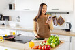 © Home-stock - Positive lady using smartphone while cutting vegetables on kitchen table, texting online or ordering products delivery from grocery store