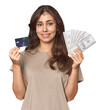 © Asier - Young Middle Eastern woman comparing credit card and dollars in studio