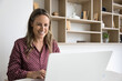 © fizkes - Enjoying job. Smiling mid aged businesswoman accountant manager remote consultant use notebook at workplace type email to client write report create sales marketing text for social media. Copy space
