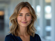 © imagemir - Smiling young woman with medium-length blonde hair in a professional setting, exudes confidence and warmth.