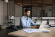 © fizkes - Authentic Indian businessman in his 30s stays busy with analysis and tech development. Successful Executive business manager engaged in online conference corporate meeting, works with laptop in office