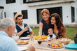 © Halfpoint - Family sitting at table and eating delicious food during spring family barbecue.